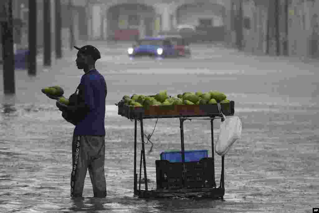 Un vendedor ofrece sus aguacates en medio de una calle anegada por las intensas lluvias asociadas a la tormenta Idalia, en La Habana, este 29 de agosto.