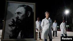 Médicos cubanos posan al lado de un cuadro del fallecido dictador Fidel Castro. (Foto: REUTERS/Alexandre Meneghini, Archivo)