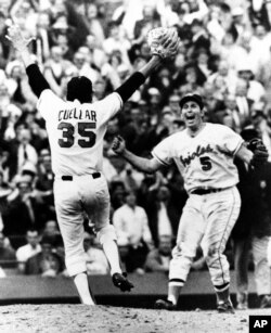 ARCHIVO - El lanzador Mike Cuellar de los Orioles de Baltimore levanta los brazos en señal de victoria mientras se apresura a encontrarse con su compañero de equipo Brooks Robinson en 15 de octubre de 1970. (Foto AP)