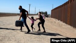 Una familia de migrantes cubanos se apresura a cruzar la frontera en Yuma, Arizona, en mayo de 2021. (Ringo Chiu/ AFP)