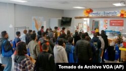 ARCHIVO - Varias personas hacen fila en el centro de bienvenida a migrantes frente a la estación de autobuses, el viernes 16 de diciembre de 2022, en Brownsville, Texas