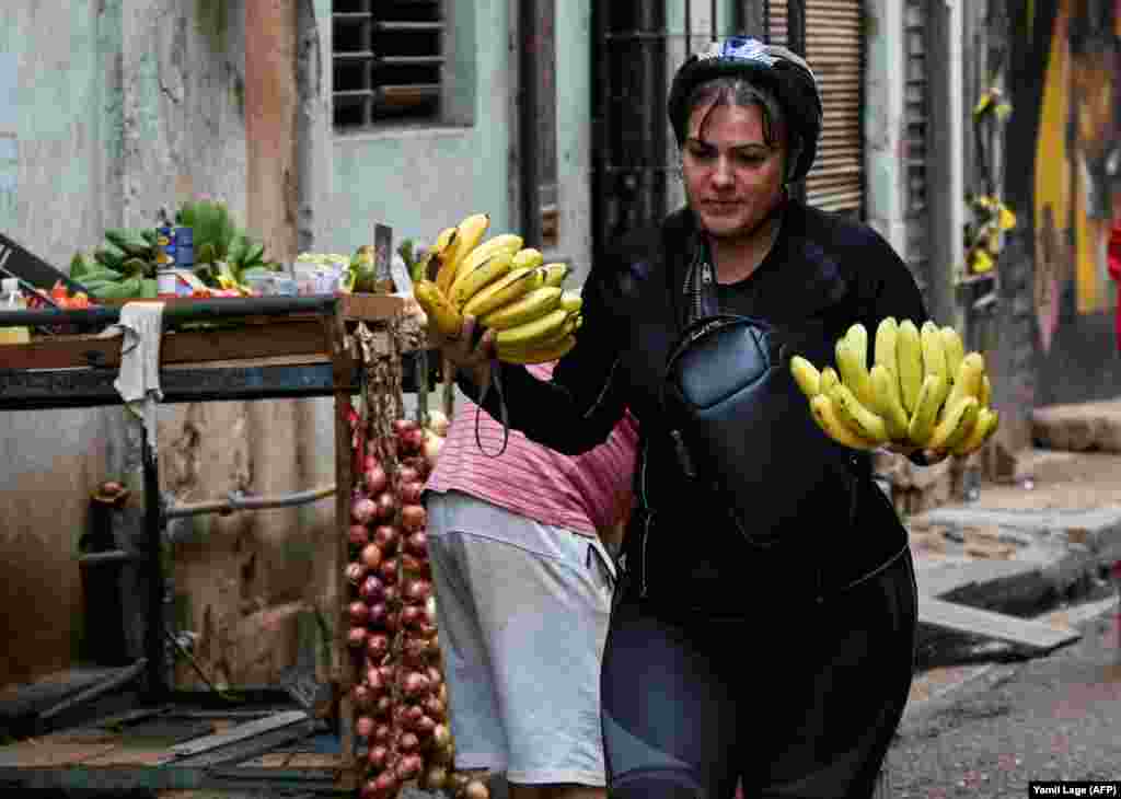 Una mujer carga dos manos de plátano por una calle de La Habana, el 20 de diciembre de 2023.