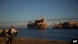 Un pescador sostiene su caña en el Malecón, donde un barco de bandera turca que transporta una planta de electricidad llega a la bahía de La Habana. (AP Foto/Ismael Francisco)