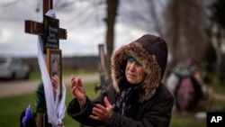 Valentyna Nechyporenko llora en la tumba de su hijo Ruslan, en su funeral, en el cementerio en Bucha, a las afueras de Kiev. (AP/Emilio Morenatti)