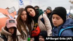 Una familia de refugiados espera en una fila en el paso fronterizo de Medyka, en el sureste de Polonia, tras huir de la guerra de la vecina Ucrania . (AP Foto/Sergei Grits