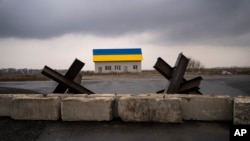 Barreras antitanque yacen frente a una casa pintada con los colores de la bandera ucraniana en las afueras de Kiev, Ucrania. (AP Foto/Rodrigo Abd)