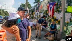 Jaime Martinez y su hija Evelyn Martinez, de Maryland, rinden homenaje a las víctimas del desplome del edificio en condominio Champlain Towers South, el jueves 8 de julio de 2021, en Surfside, Florida. (Pedro Portal/Miami Herald vía AP)