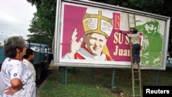 Un trabajador cubre una valla publicitaria que solía tener un cartel de Fidel Castro y Camillo Cienfuegos con un nuevo cartel de bienvenida al Papa Juan Pablo II, en La Habana, en enero de 1998. (Foto: Reuters/Archivo)