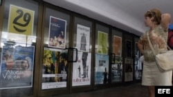 Una mujer observa varios carteles de las películas que exhibe un cine en La Habana (Cuba).