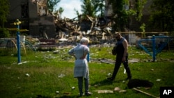 Residentes de pie junto a una escuela destrozada en un ataque ruso en Bakhmut, en el este de Ucrania. (AP Foto/Francisco Seco)