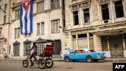 Un bicitaxi y un almendrón circulan por La Habana. (Archivo)