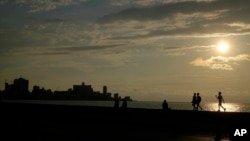 Cubanos pasean por el Malecón de La Habana al atardecer.