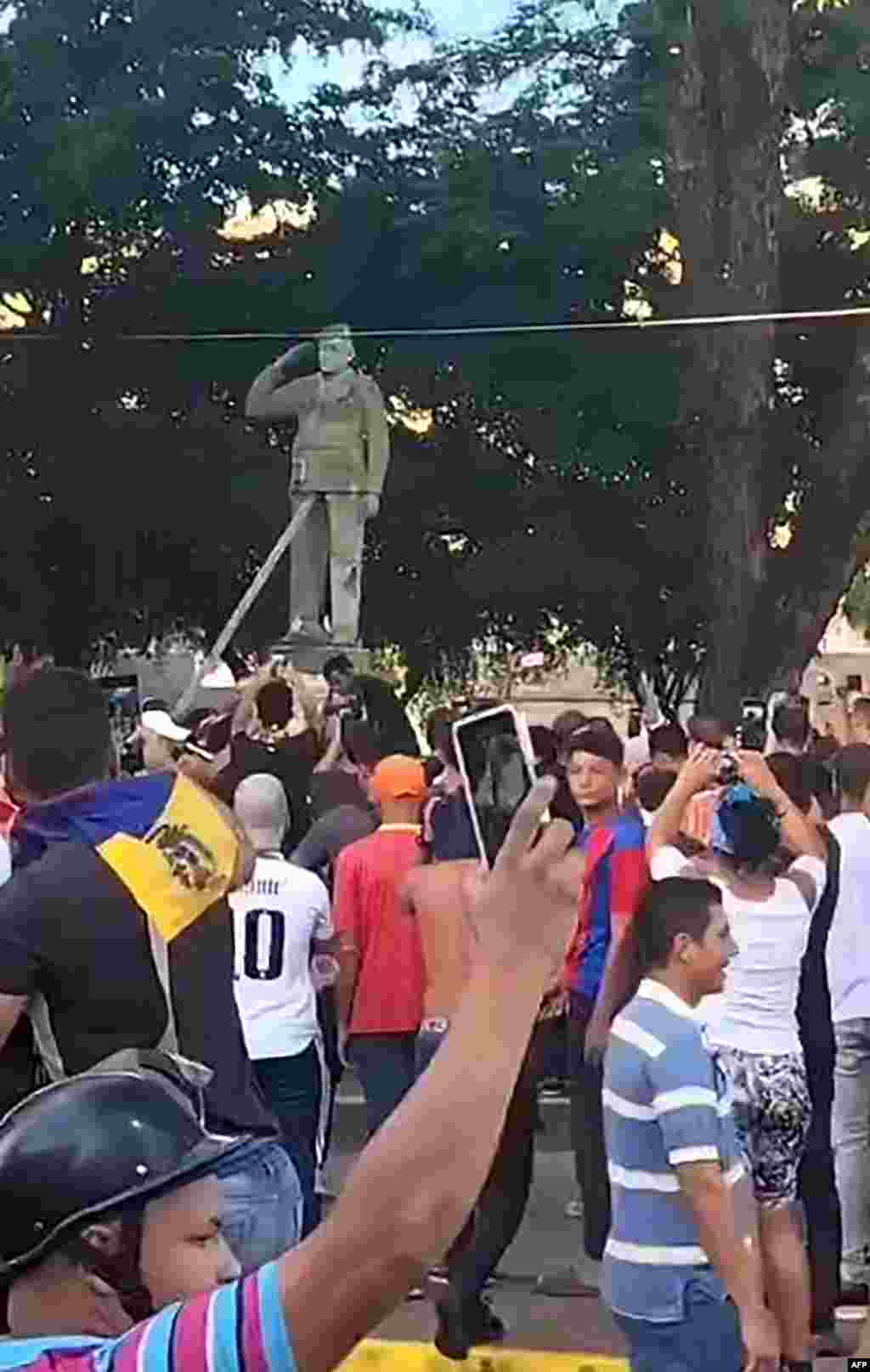 Esta fotografía de un video UGC tomada el 29 de julio de 2024 y publicada como cortesía del usuario @AndresZX17 muestra a manifestantes antigubernamentales vitoreando mientras derriban una estatua del ex presidente venezolano Hugo Chávez en Calabozo, Venezuela, el 29 de julio de 2024. en medio de los disturbios por la disputada reelección del presidente Nicolás Maduro.