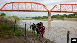 Tres migrantes cubanos llegan a suelo estadounidense tras cruzar el Río bravo en Eagle Pass, Texas, el 22 de mayo de 2022. (AP Foto/Dario Lopez-Mills)