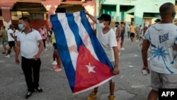 El joven Elías Rizo León sostiene una bandera manchada de sangre en las manifestaciones del 11 de julio de 2021. Foto AFP/ Adalberto Roque