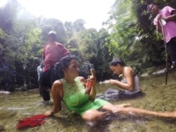 Un descanso breve después de cruzar un río en el Tapón de Darién, la jungla salvaje que envuelve la frontera entre Colombia y Panamá. (Fotografía de Lisette Poole. Screenshot NPR)