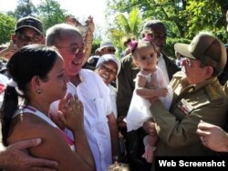 Raúl Castro carga a una niña durante su paseo por las calles de Santiago de Cuba.