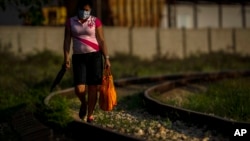 Una mujer camina con provisiones a lo largo de la línea del ferrocarril en una zona rural de La Habana. (AP/Ramón Espinosa)