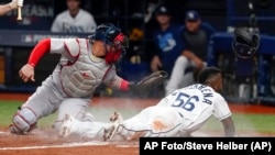 El cubano Randy Arozarena (56), de los Rays de Tampa Bay, se roba el home frente al receptor puertorriqueño Christian Vázquez, de los Medias Rojas de Boston, en la Serie Divisional de la Liga Americana en St. Petersburg, Florida, el jueves 7 de octubre de