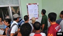 Varias personas leen una cartelera en una oficina municipal de trabajo.