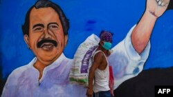 Homeless con mascarilla en Nicaragua, pasa frente a imagen publicitaria del Presidente Ortega