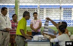 Miembros de una junta receptora de votos (JRV) muestran una boleta a un hombre durante los comicios generales en Nicaragua.