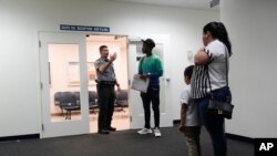 ARCHIVO - Un guardia dirige a la gente a una sala de un tribunal de inmigración en Miami. (Foto AP/Wilfredo Lee, Archivo)