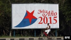 Un hombre pasa en bicicleta frente a una valla alusiva al nuevo año el miércoles 31 de diciembre de 2014, en La Habana (Cuba).