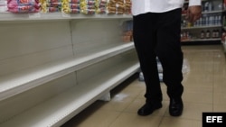 Un hombre camina por un pasillo de supermercado frente a estanterías desabastecidas, en Caracas (Venezuela).