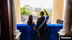 Nayib Bukele junto a su esposa Gabriela de Bukele desde el balcón del Palacio Nacional tras recibir la banda presidencial, durante la ceremonia de juramento de su segundo mandato en San Salvador, el 1 de junio de 2024. Presidencia de El Salvador /Folleto vía REUTERS