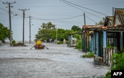 Un hombre navega en una embarcación hacia zonas seguras en una calle inundada tras el paso del huracán Helene en Guanimar, provincia de Artemisa, Cuba, el 25 de septiembre de 2024. (Foto de YAMIL LAGE / AFP)