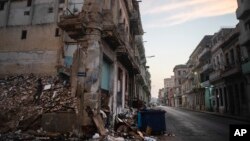 Edificios ruinosos y derrumbados bordean la calle San Lázaro, donde un hombre, a la izquierda, recoge ladrillos en el centro de La Habana, el martes 10 de octubre de 2023. (Foto AP/Ramón Espinosa)