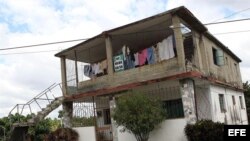 Un hombre camina junto a una casa que se encuentra a la venta.