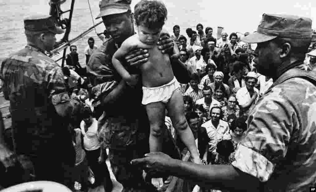 Un marine de EEUU ayuda a desembarcar a un ni&#241;o cubano tras su llegada a las costas de Florida en el &#233;xodo del Mariel. AP Photo/Fernando Yovera)