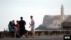 Varios jóvenes toman cerveza en el malecón habanero.