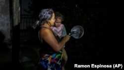 Una madre con su hija en brazos protesta golpeando una cazuela en medio del apagón general, en La Habana, el domingo 20 de octubre de 2024. (Foto AP/Ramon Espinosa)