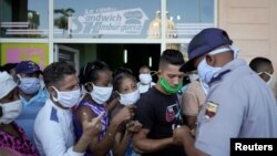 Un policía organiza una fila de personas que esperan para comprar alimentos en La Habana, el 3 de abril del 2020.