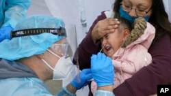 Kim Tapia sostiene a su nieta Amariah Lucero, de 3 años, mientras le realizan la prueba de COVID-19 en Salt Lake City, Utah.