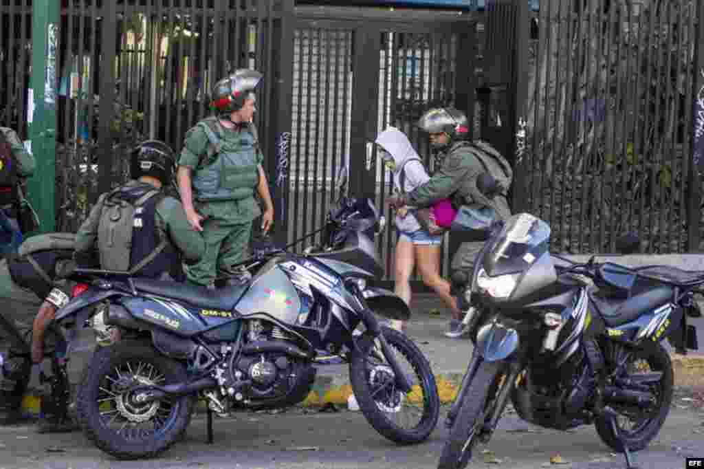 Miembros de la Guardia Nacional Bolivariana detienen a una manifestante