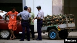 La policía registra el cargamento de un vendedor de piñas / Foto: Desmond Boylan (Reuters)