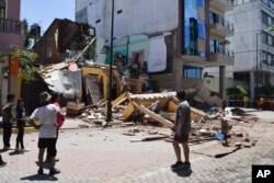 Residentes miran un edificio que se derrumbó después de que un terremoto sacudiera Machala, Ecuador. (Foto AP/Jhonny Crespo)