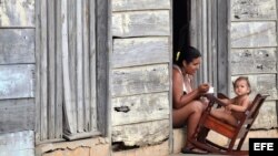 Una madre alimenta a su hija en la puerta de su vivienda en Baracoa. Archivo.