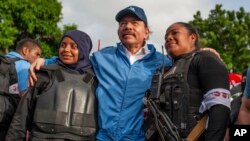 El gobernante Daniel Ortega, entre dos agentes policiales. (AP Foto/Cristóbal Venegas).