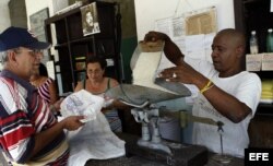 Un bodeguero despacha a un anciano los productos que se distribuyen mediante la libreta de racionamiento en Cuba.