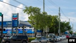 Varios vehículos hacen largas filas en una gasolinera en la ciudad de Miami. 