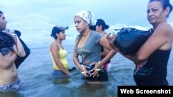 Liset y Marta se preparan para abordar un bote en Colombia mientras se acercan a la frontera con Panamá. (Fotografía de Lisette Poole. Screenshot NPR)