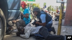 Periodistas se cubren del cruce de disparos entre pandillas y la policía en Puerto Príncipe, Haití, el lunes 11 de noviembre de 2024. (AP Foto/Odelyn Joseph)