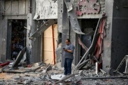 Un palestino frente a unas tiendas dañadas tras los ataques aéreos israelíes que destruyeron una torre, el primer día de las celebraciones del Eid al-Fitr, en Gaza. REUTERS/Suhaib Salem