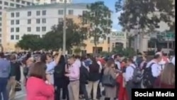 Un grupo de personas se reúne a cielo abierto frente a un supermercado Publix después de abandonar los edificios circundantes en el área del centro comercial Dadeland.