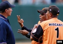 El director técnico de Villa Clara, Víctor Mesa (c) es aguantado por el entrenador de pitcheo de su equipo, José Ramón Riscart (d) mientras discute con el árbitro principal Pedro Morgado (i.) durante un partido en el estadio Latinoamericano.